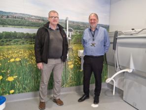 Two people standing inside a changing places facility with a large image of Rotherham's green spaces across the back wall.